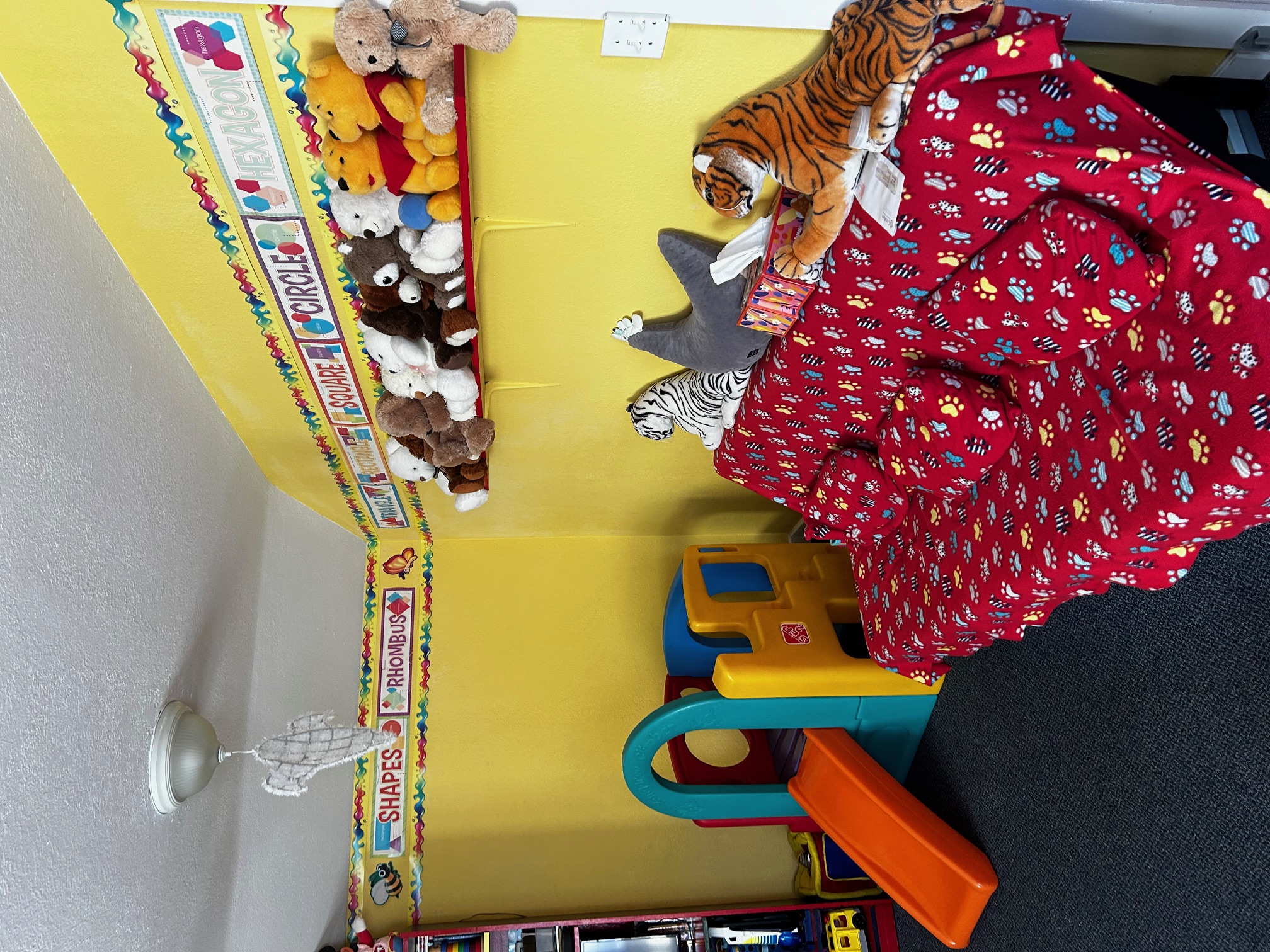 A corner of the daycare, with a small play structure, a couch and some plushies.